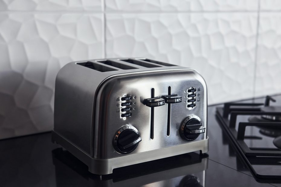 Close up view of silver colored toaster that standing on gas stove indoors in kitchen