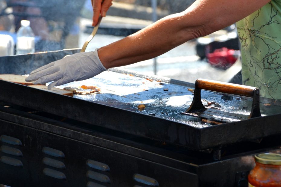 Woman frying food on a hot griddle at an outdoor festival.